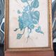 Decorative table with vintage blue flowers in a golden frame.