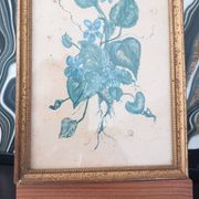 Decorative table with vintage blue flowers in a golden frame.