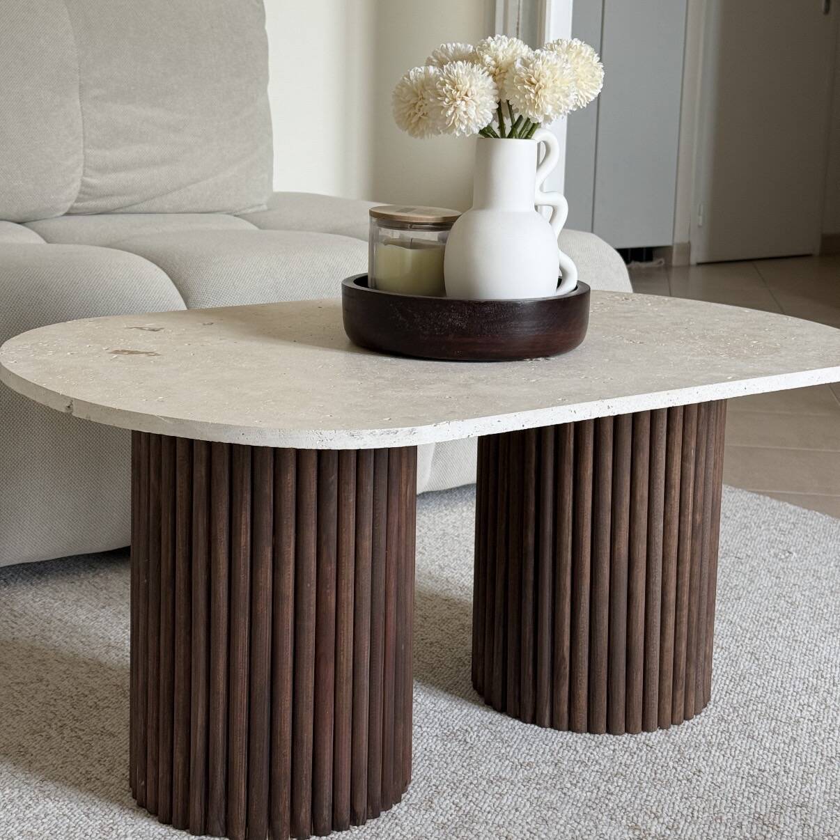 Oval coffee table in travertine and fluted wood.
