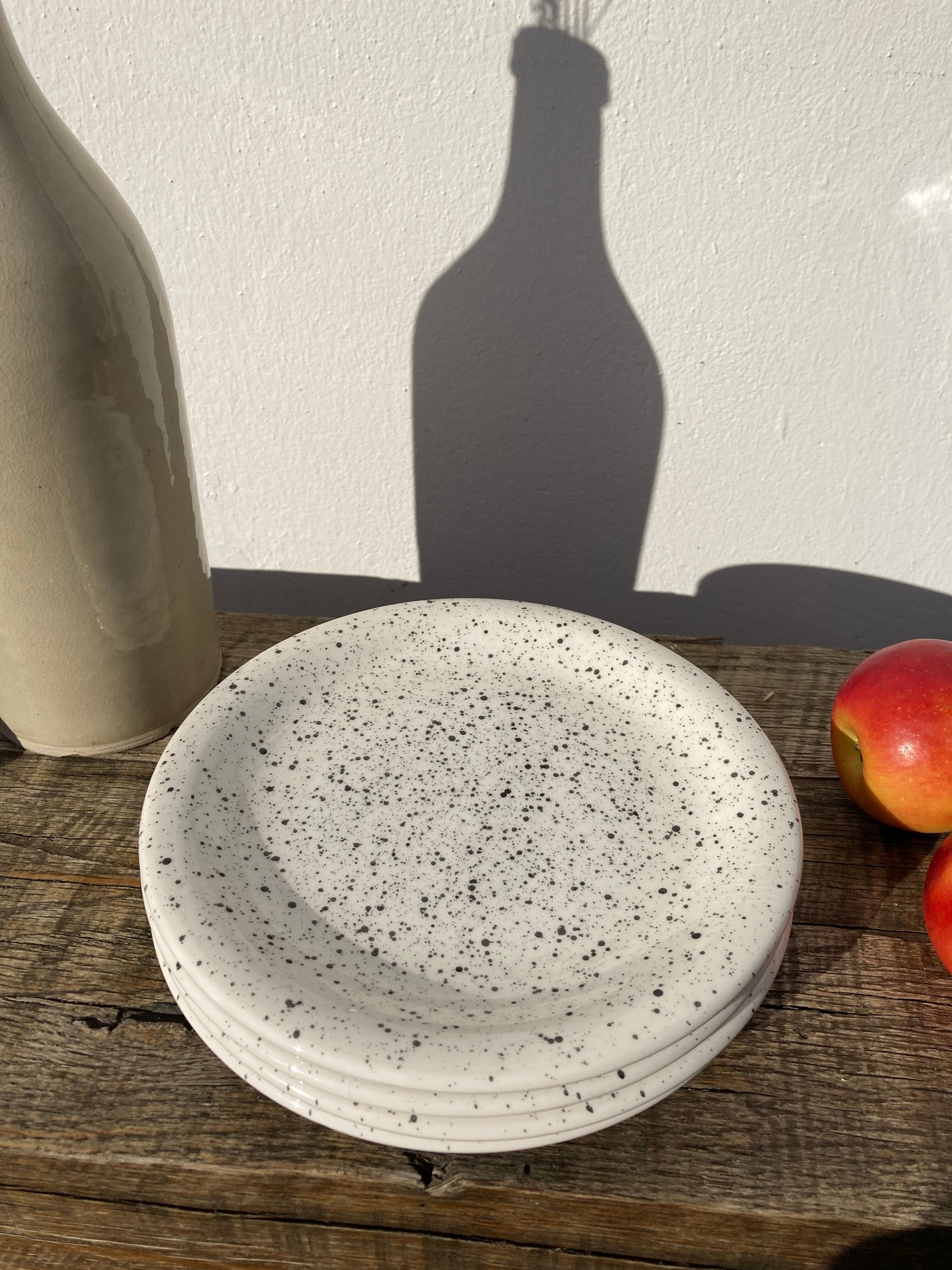 4 black speckled dessert plates on a vintage white background