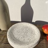 4 black speckled dessert plates on a vintage white background