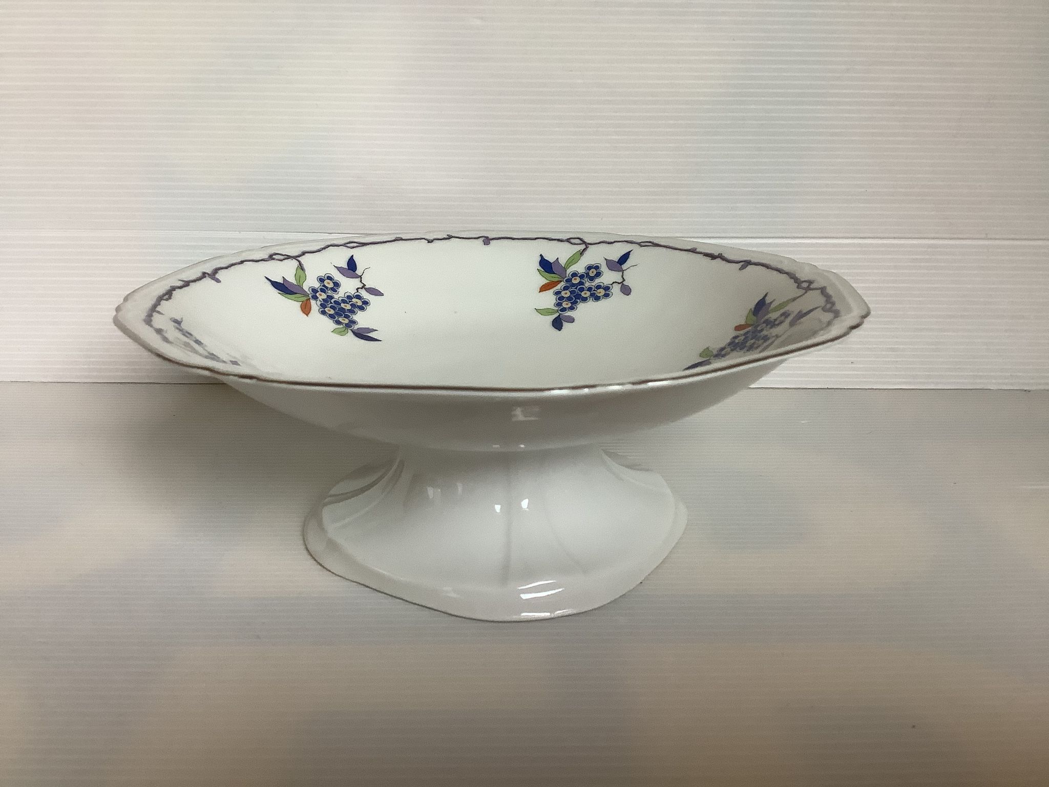Old shower tray with silver trim and forget-me-not flowers.