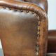 Sheepskin wingback armchair with decorative nails and black piping