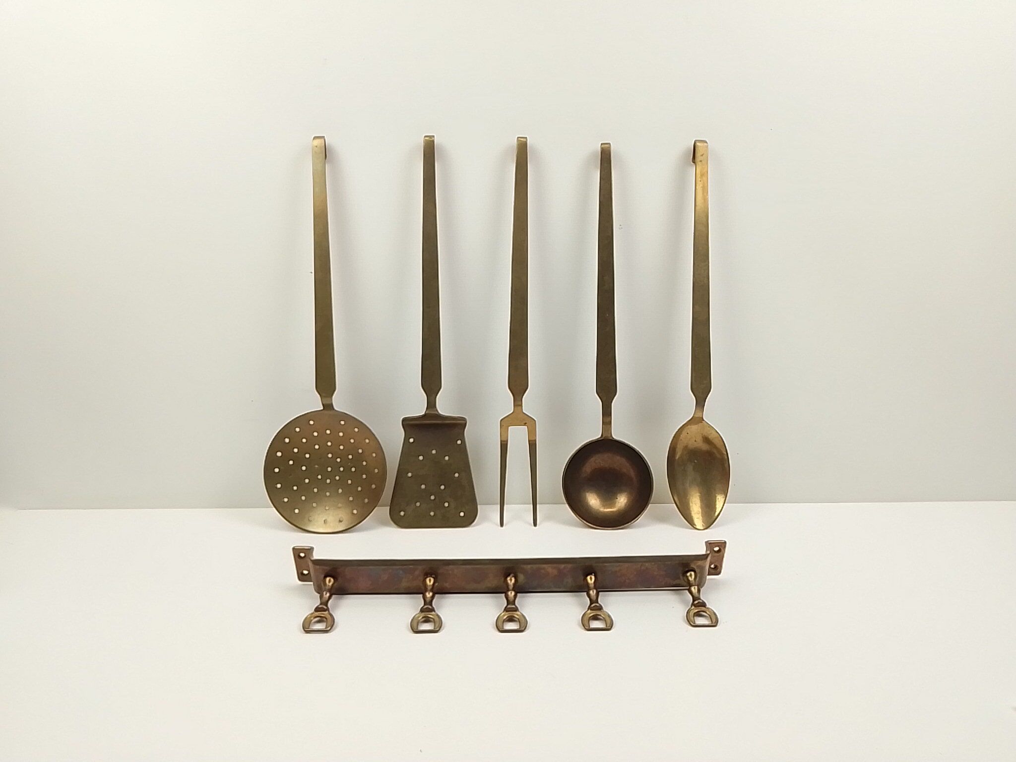 5 kitchen utensils and a brass wall mount
