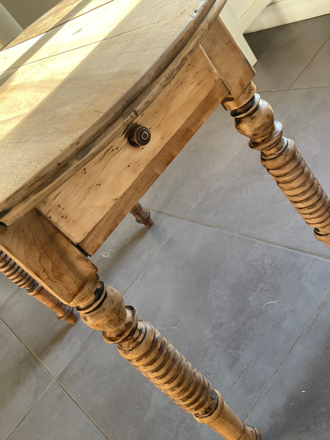 Oval wooden table with drop-leaf edges.