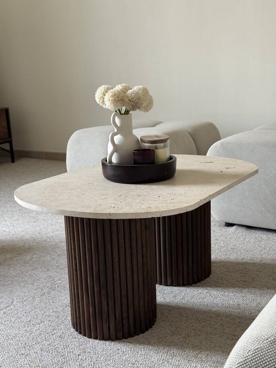 Oval coffee table in travertine and fluted wood.