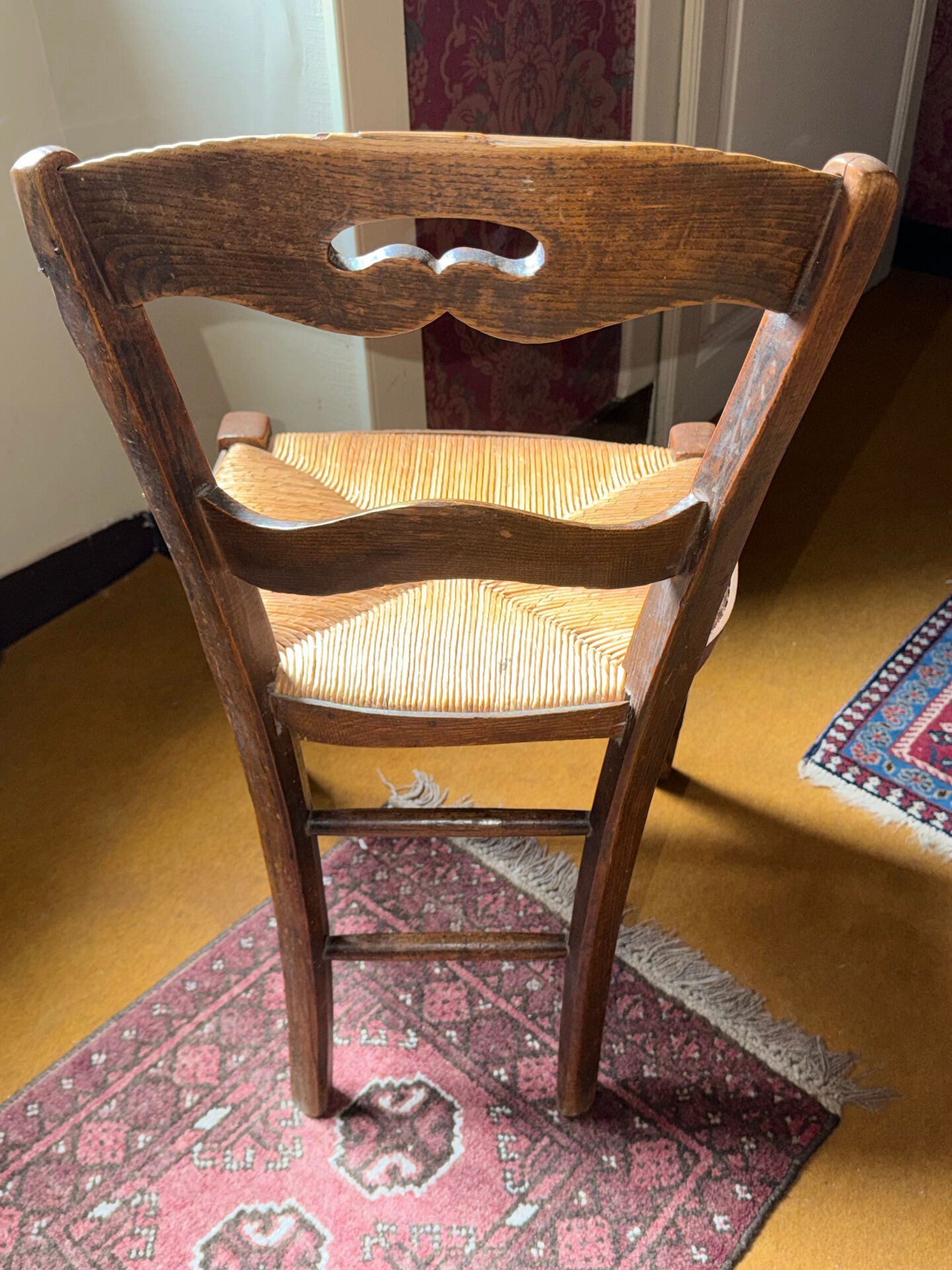 Old rustic wooden chair – carved backrest – seat in fibres