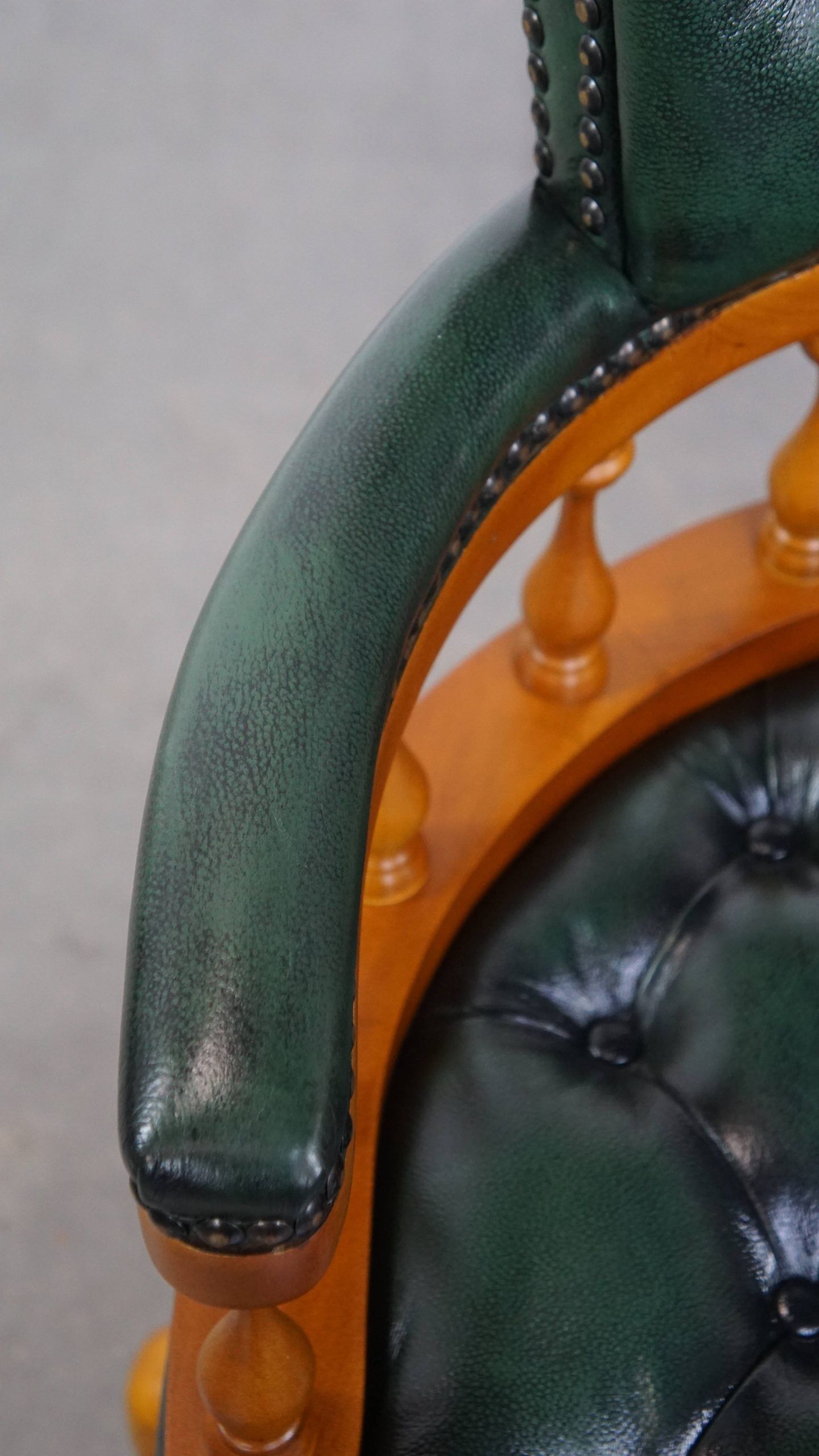 Classic green leather Chesterfield office chair on wheels.