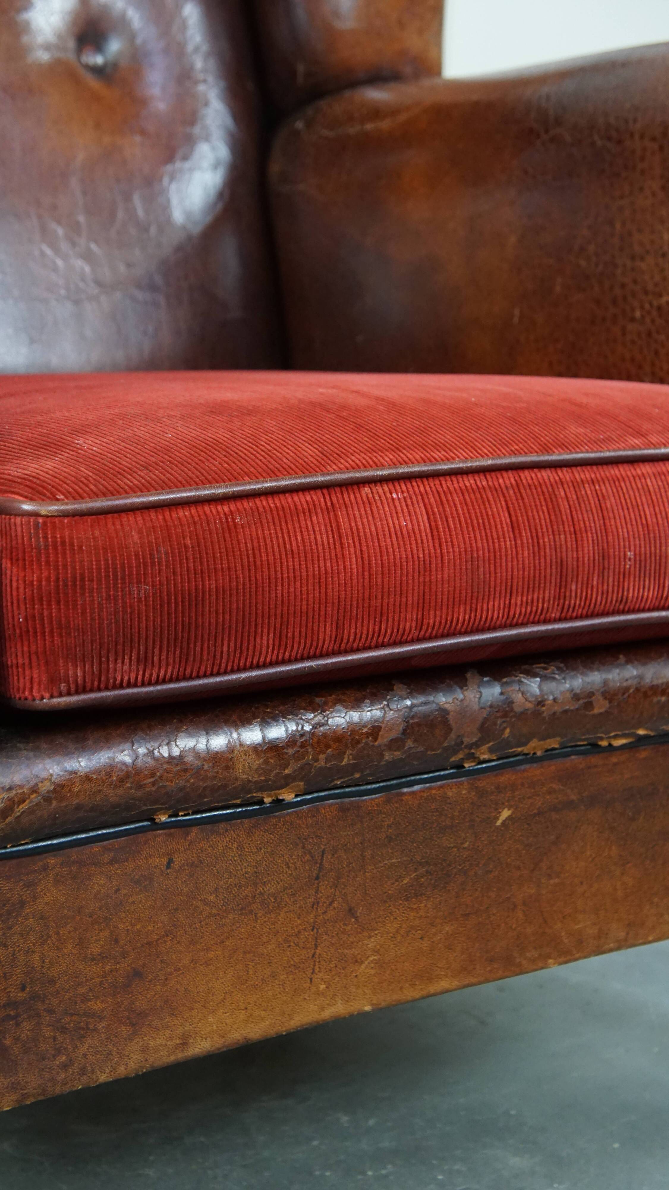 Sheepskin leather wingback chair with a red corduroy seat cushion