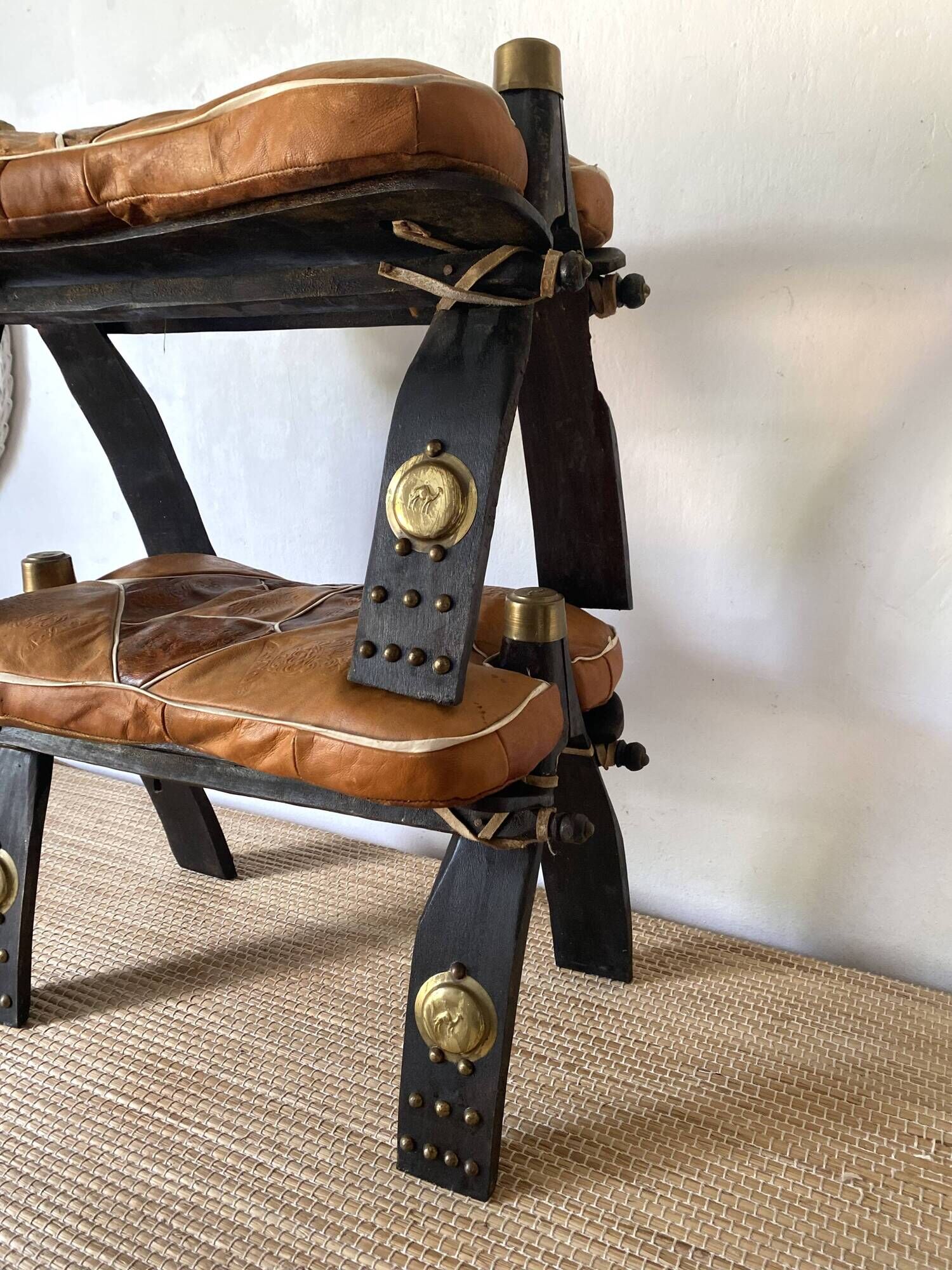 Pair of low Egyptian stools, camel saddles in wood, leather and brass