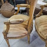 A pair of gilded wooden armchairs in the Louis XVI style.