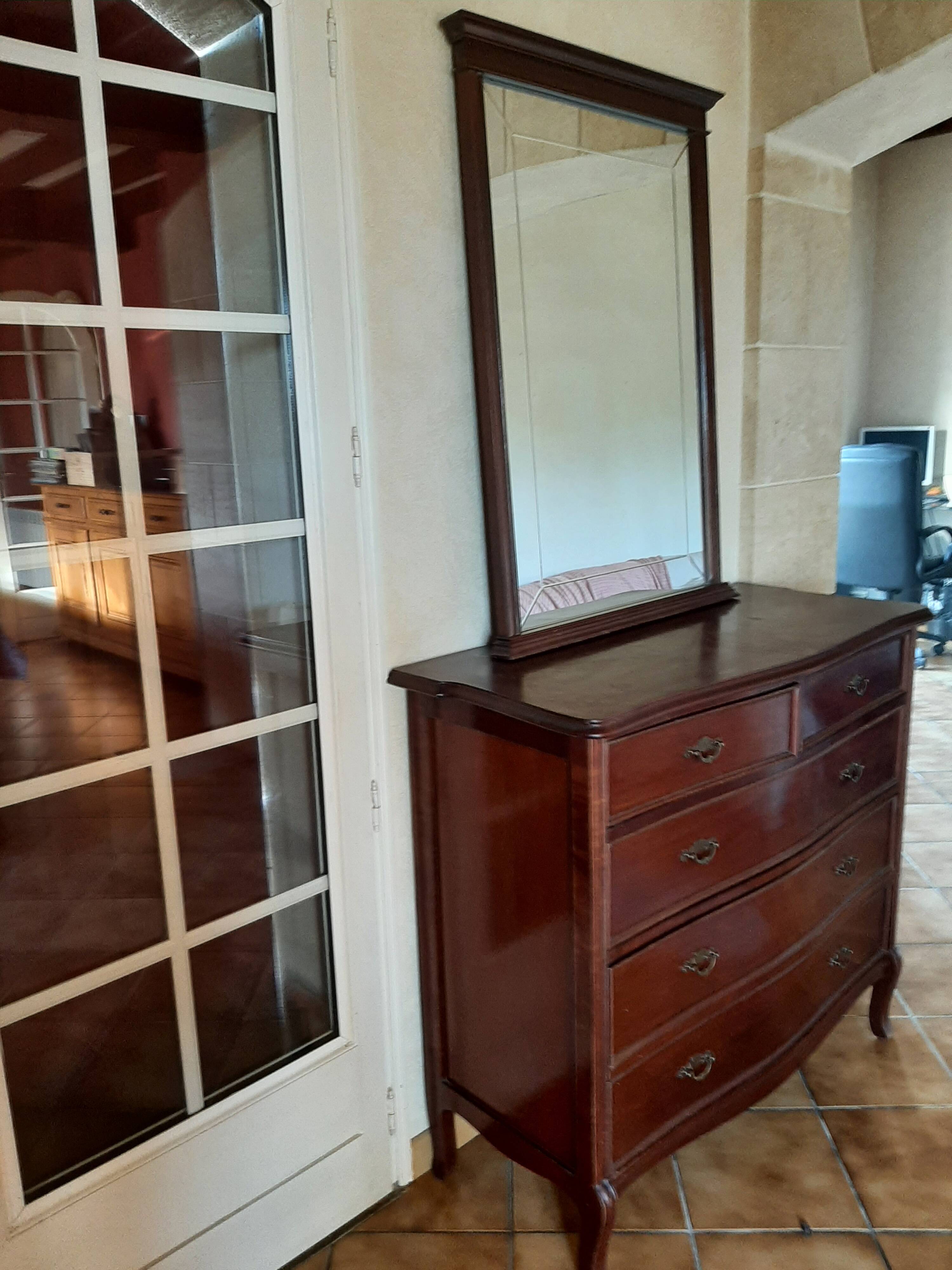 Style set: bevelled mirror and curved wooden chest of drawers.