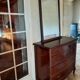 Style set: bevelled mirror and curved wooden chest of drawers.