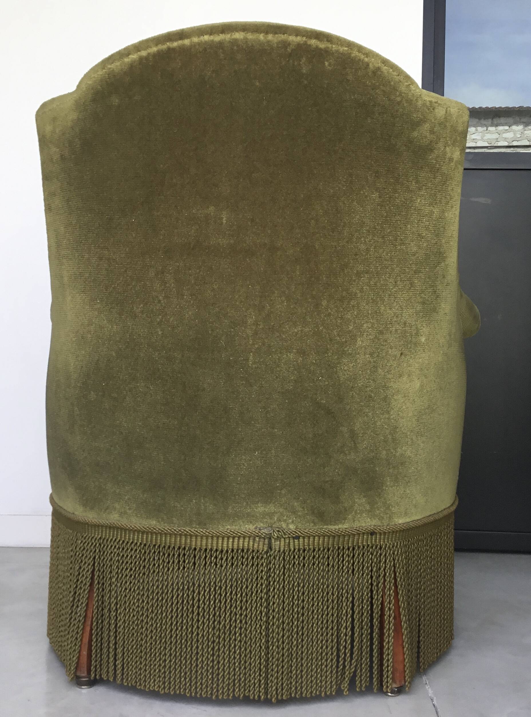 Olive green toad armchair with smooth velvet fringes.