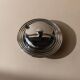 Vintage 1970s condiment pot made of glass and stainless steel with a lid, complete with a matching spoon.