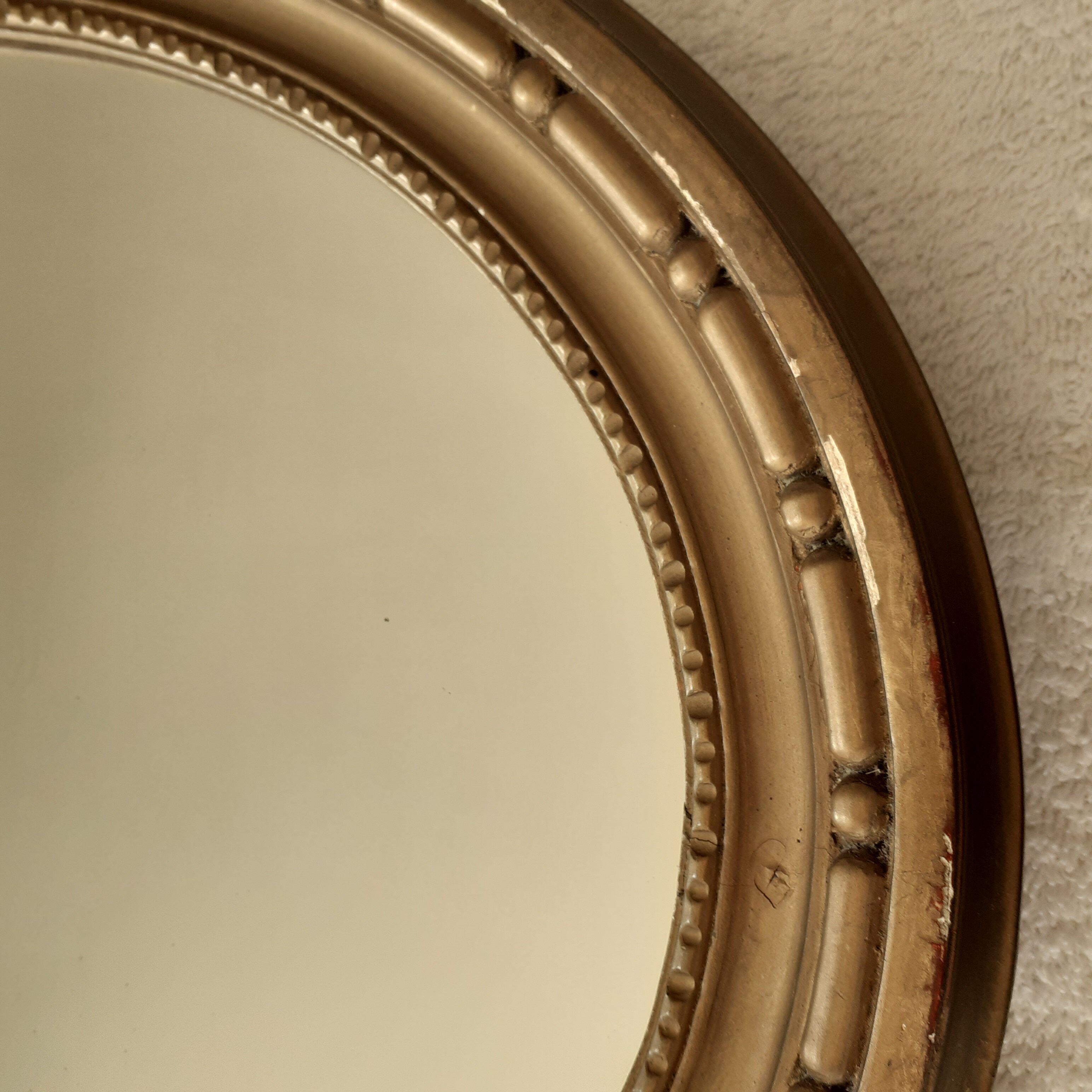 Old oval wooden mirror, surmounted by a knot