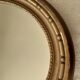 Old oval wooden mirror, surmounted by a knot