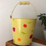 Small metal bucket with floral print on a yellow background