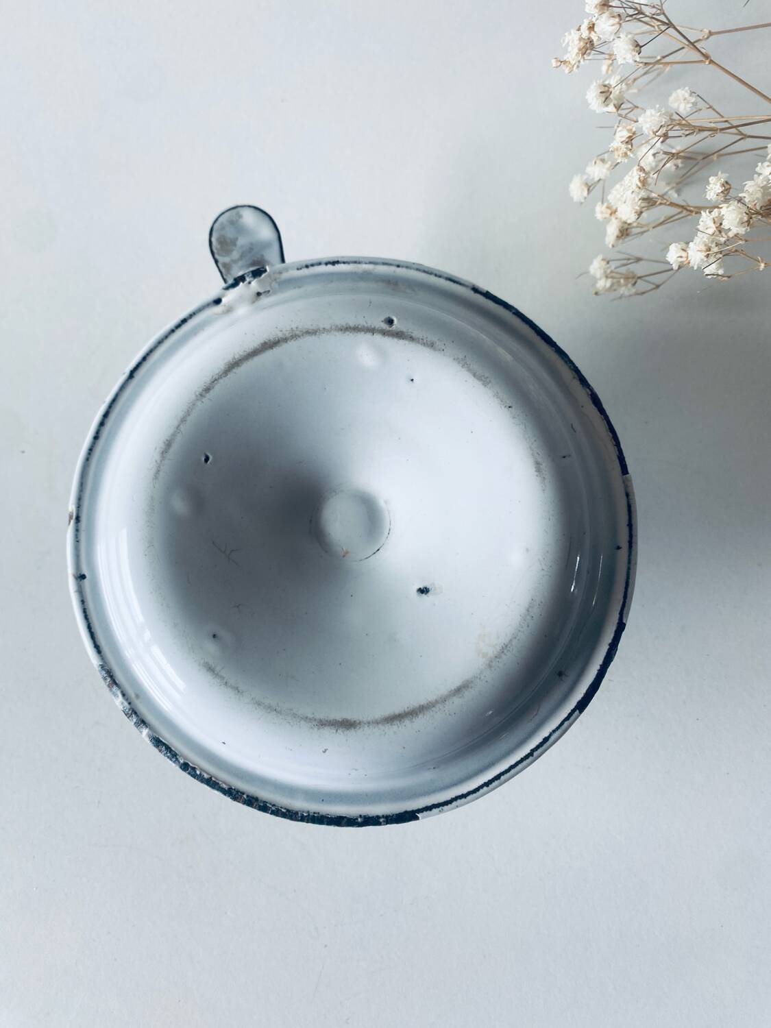 Old candle holder in white enameled metal