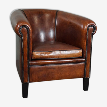 Sheepskin club chair with black piping and decorative studs
