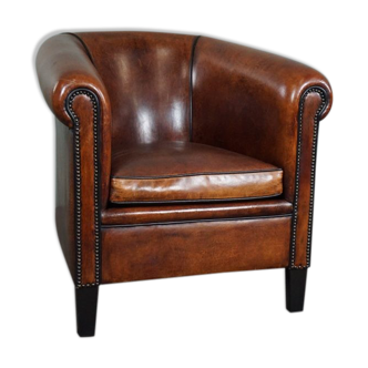 Sheepskin club chair with black piping and decorative studs
