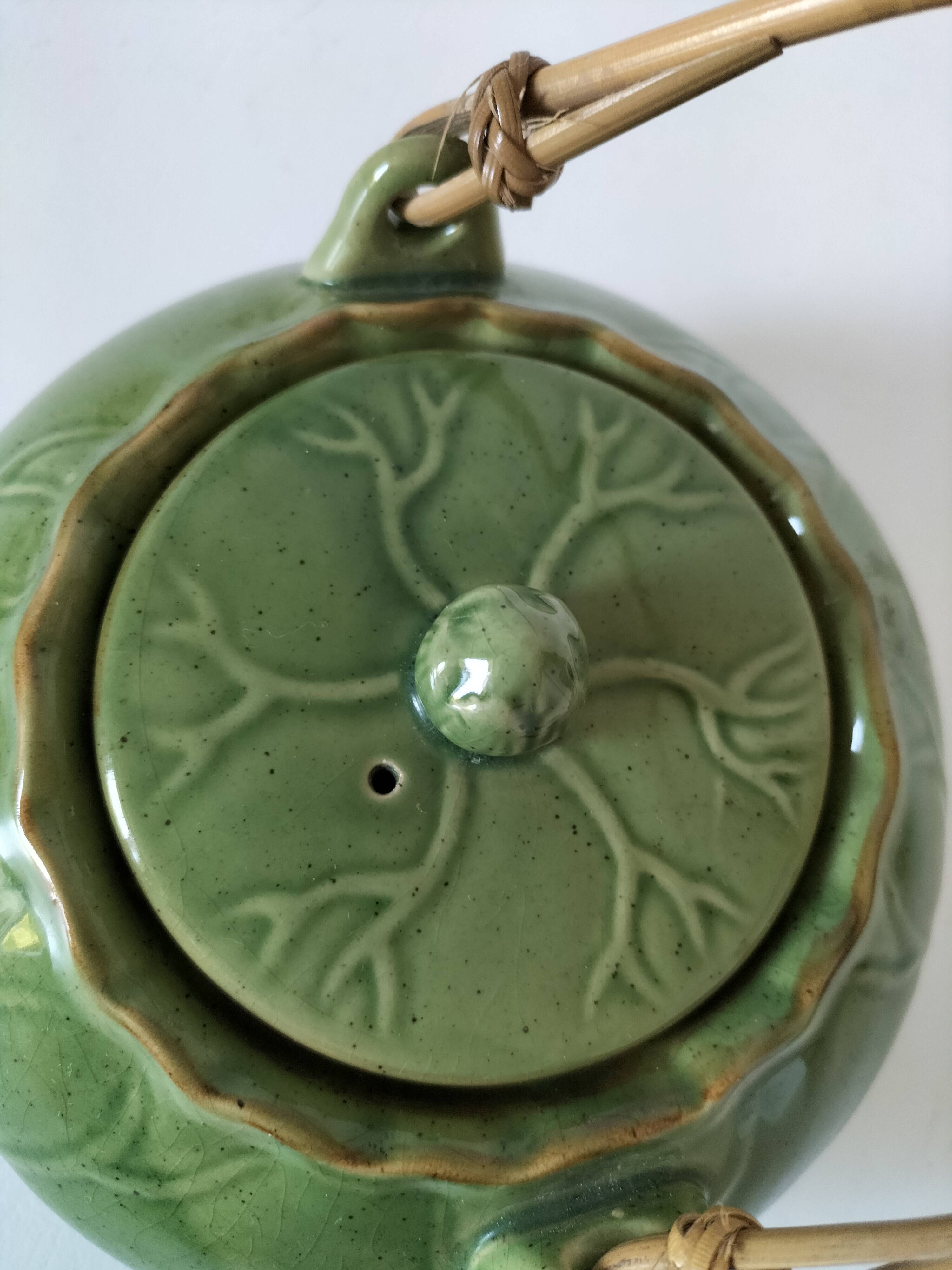 Vintage green teapot with lotus decoration and bamboo handle.