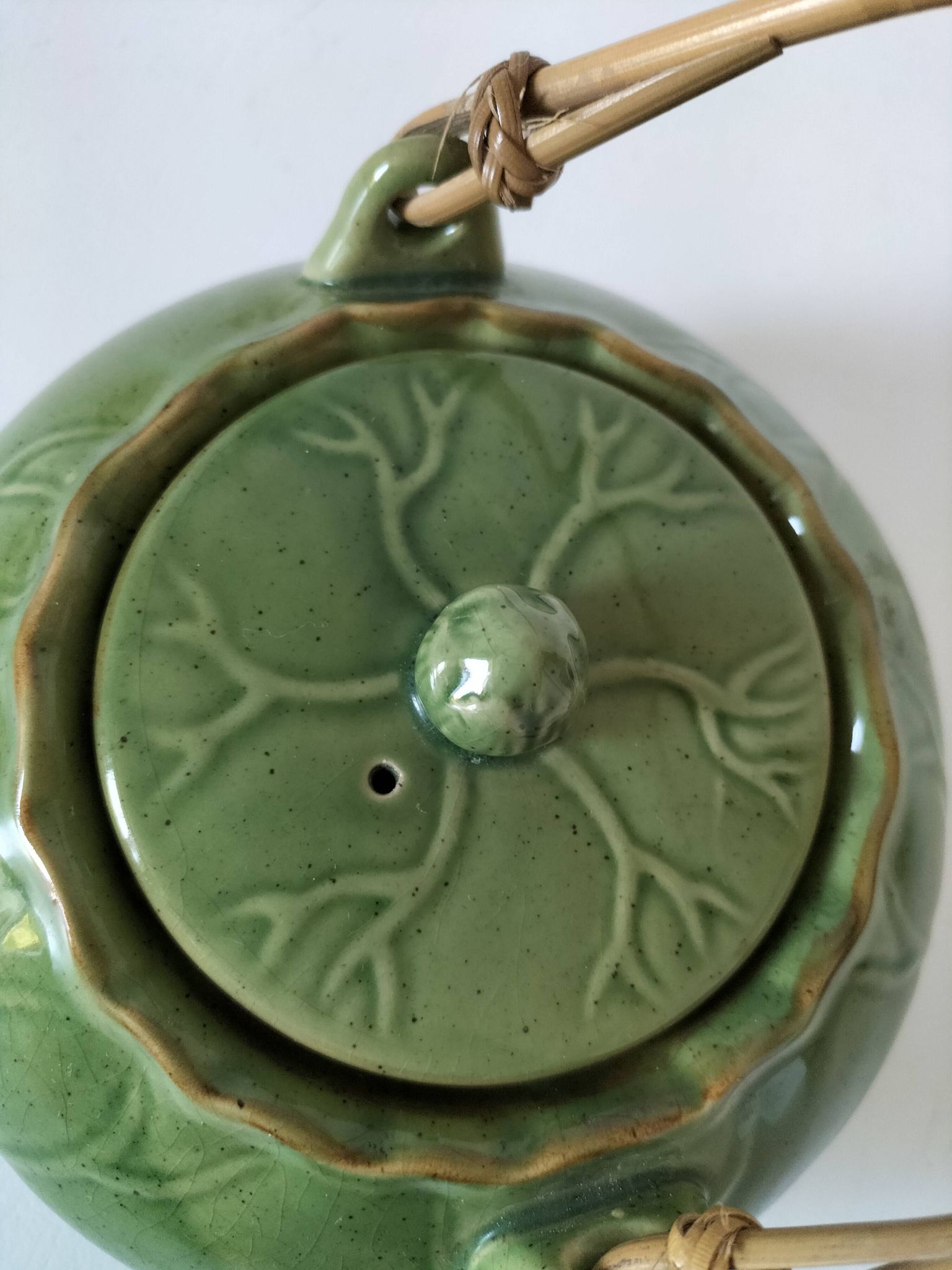 Vintage green teapot with lotus decoration and bamboo handle.