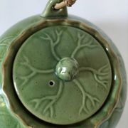 Vintage green teapot with lotus decoration and bamboo handle.