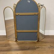 Vintage triptych mirror in brass with wall lights.