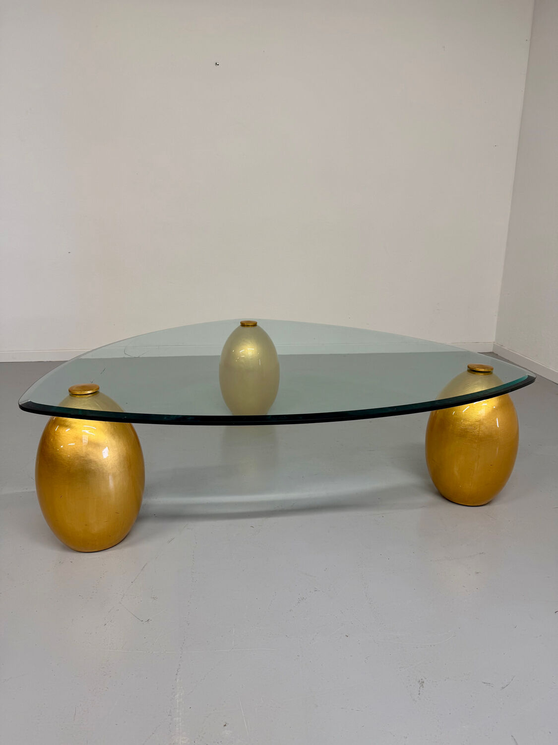 Vintage Italian design coffee table with a glass top and gold base, dating from the 1980s.
