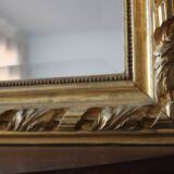 Miroir ancien doré surmonté d'un fronton et glace biseautée