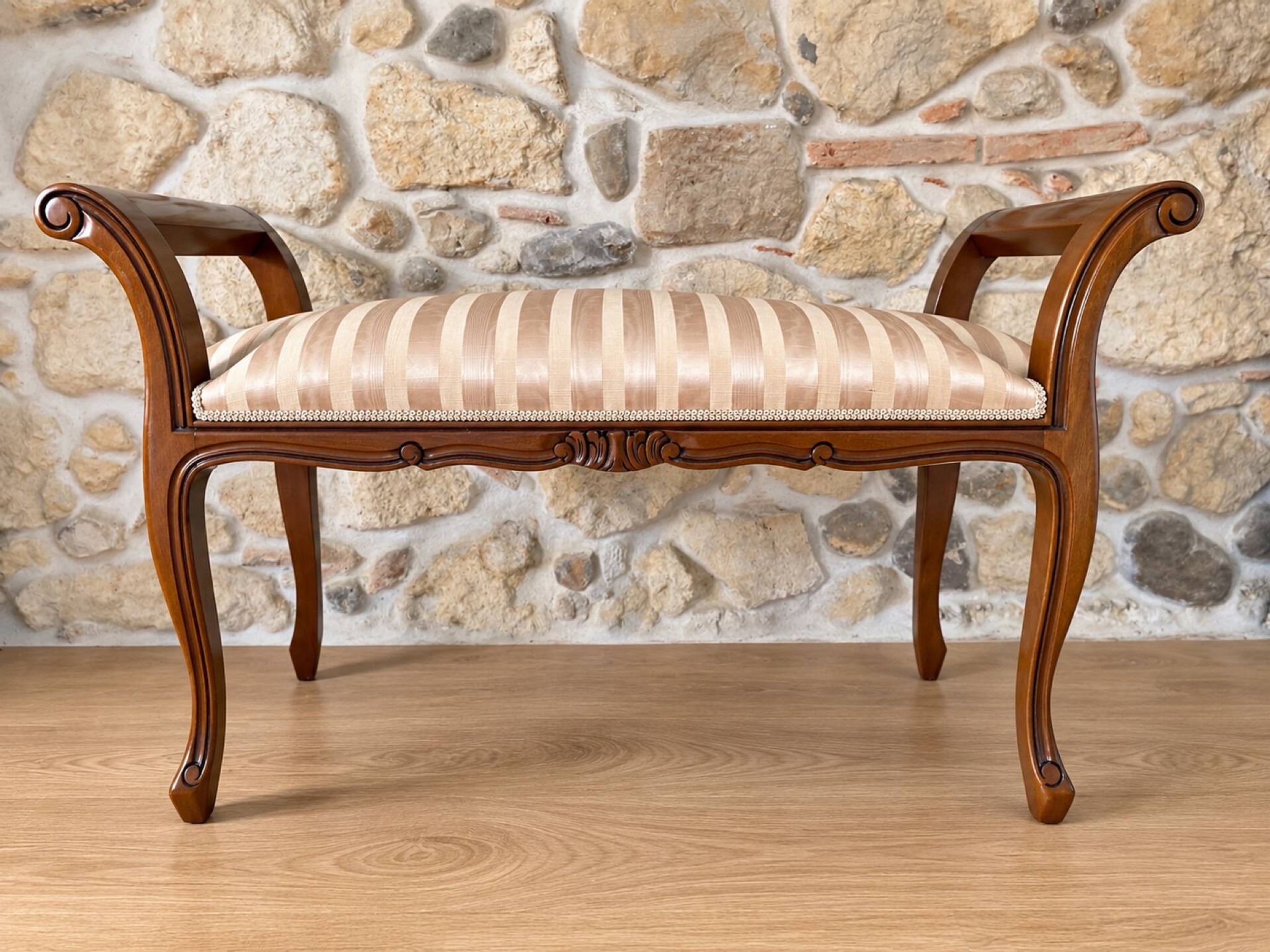 Two-seater bench in carved wood, with curved armrests.