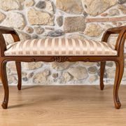 Two-seater bench in carved wood, with curved armrests.