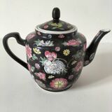 Vintage Chinese teapot with floral polychrome decoration on a black background.