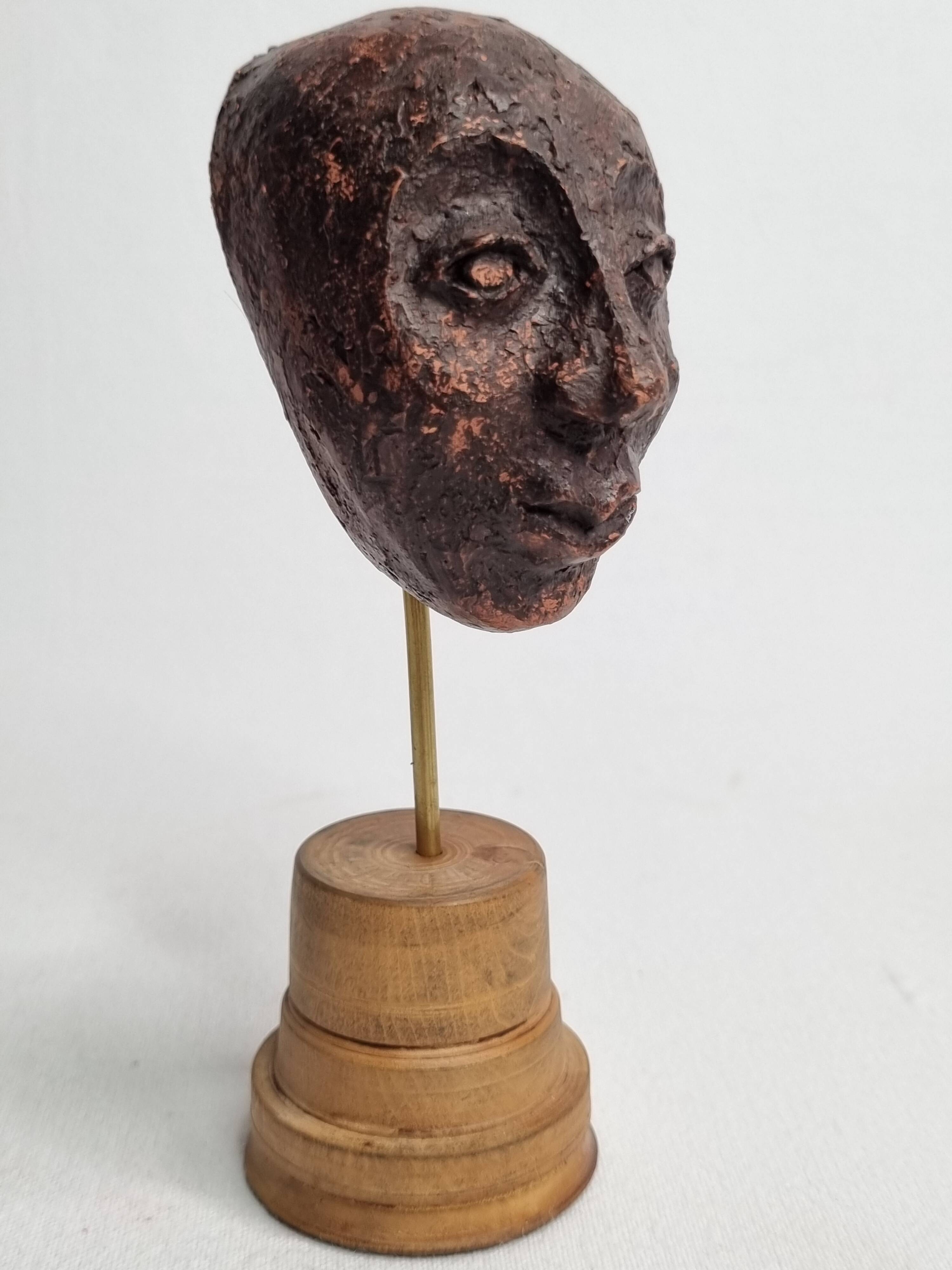 Expressive sculpted head in patinated terracotta on wooden base, 14 cm