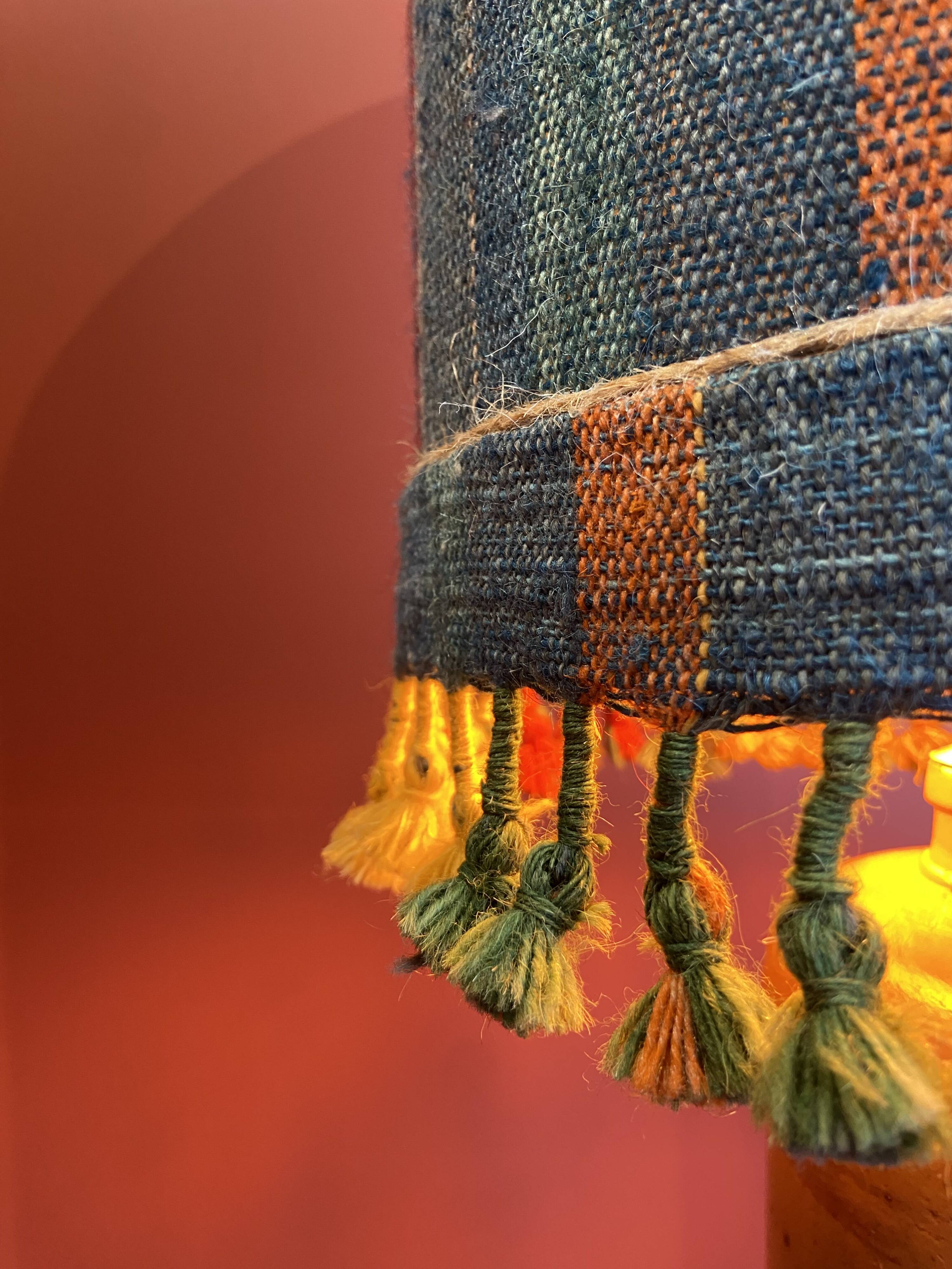 "Stoneware Bottle Lamp" with a multicoloured blue lampshade handwoven in India.