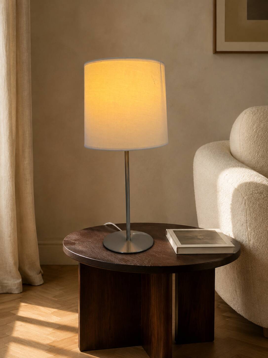 Large brushed metal table lamp with an ecru shade.