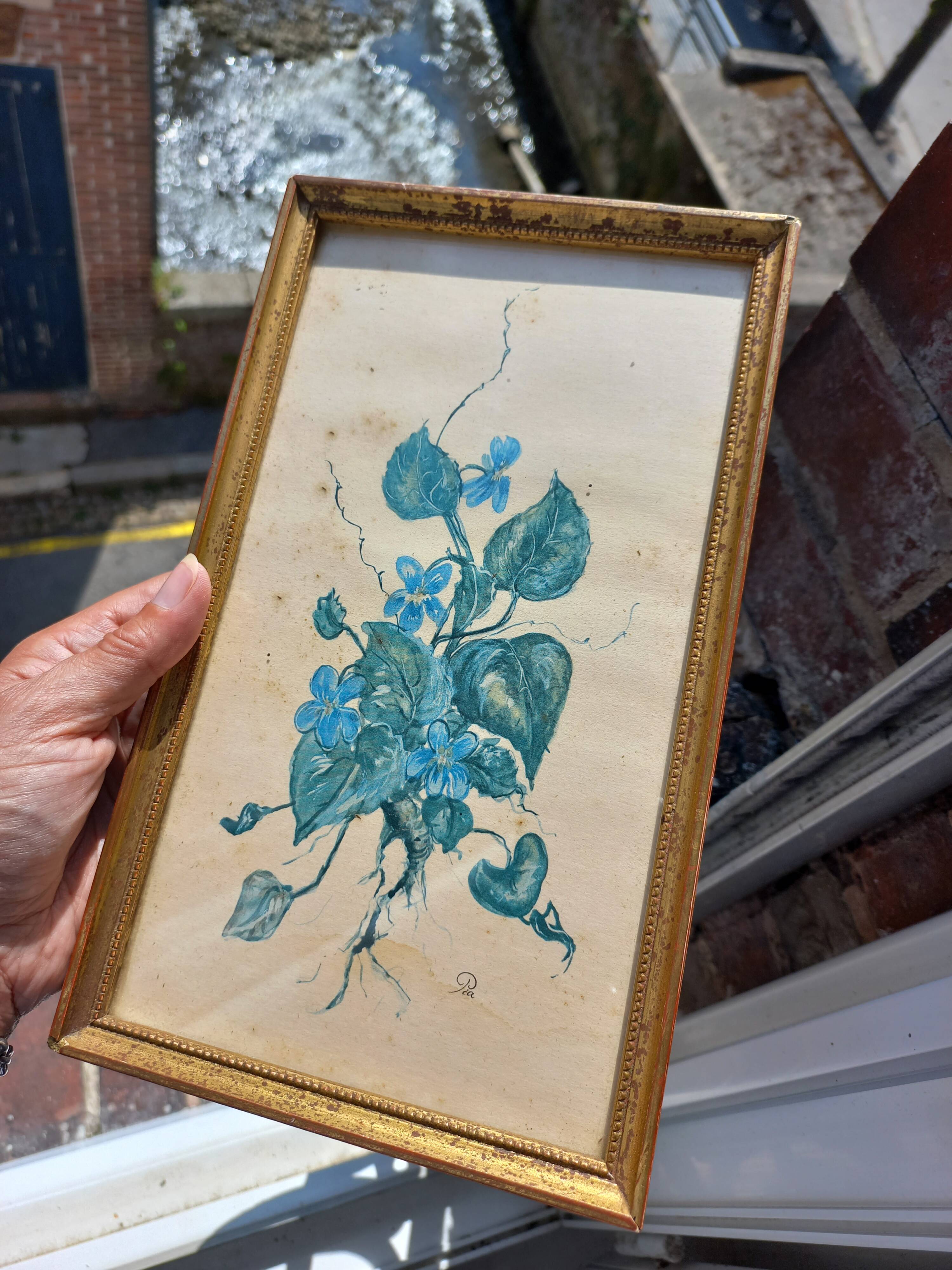 Decorative table with vintage blue flowers in a golden frame.