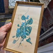 Decorative table with vintage blue flowers in a golden frame.