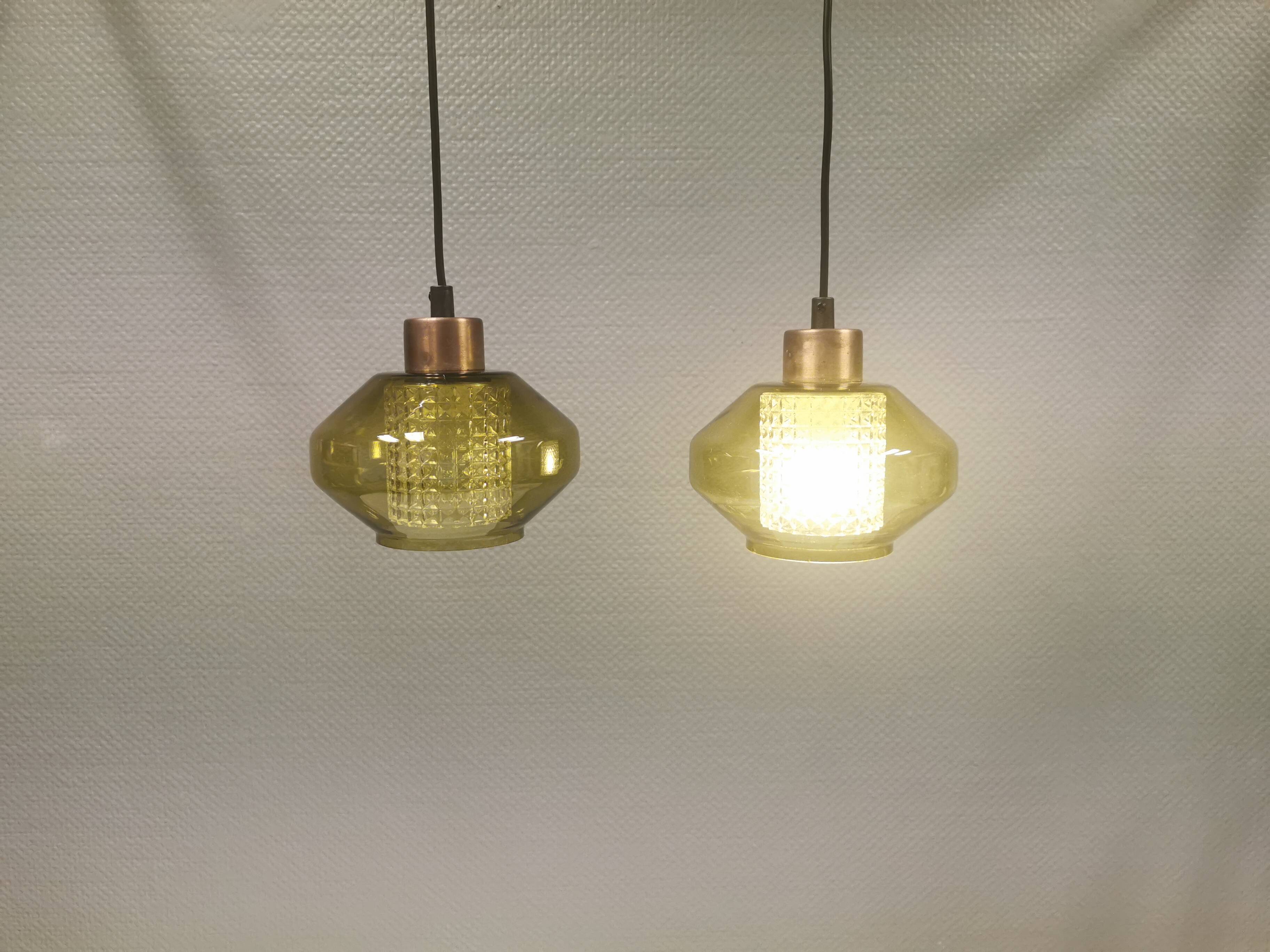 Hanging lamp with an outer shade of olive green glass and an inner shade of clear, crystal glass.