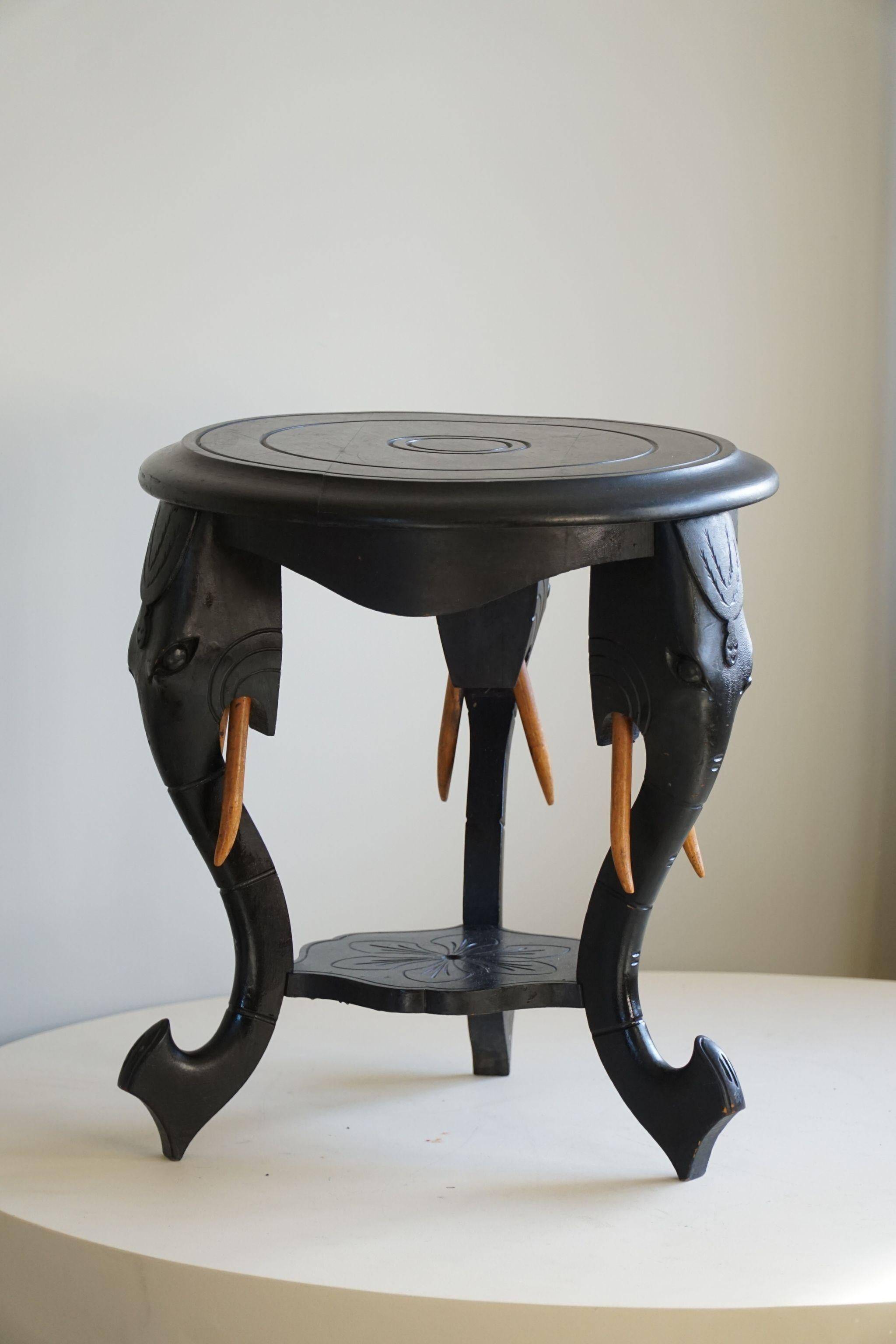 Side table in hardwood ebony with three elephant head-shaped legs, Eastern India, 1920s.