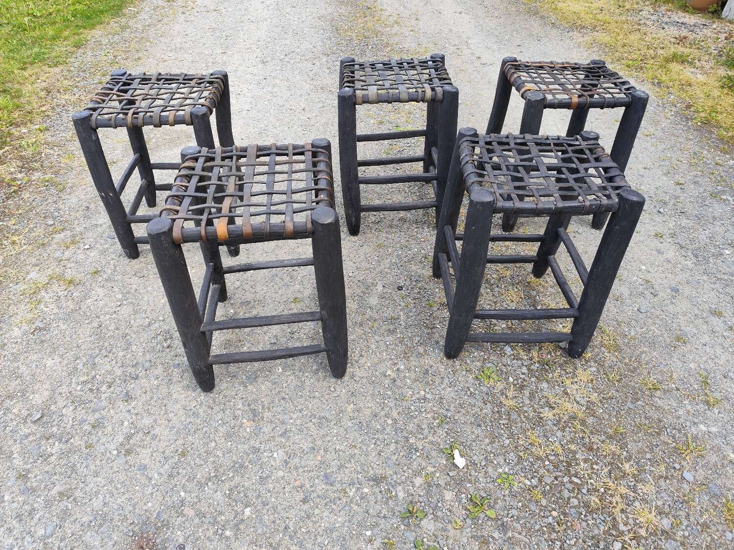 5 blackened wooden stools with woven leather seats by Nina Kaufmann
