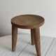 Antique stool made of raw wood carved from a single trunk