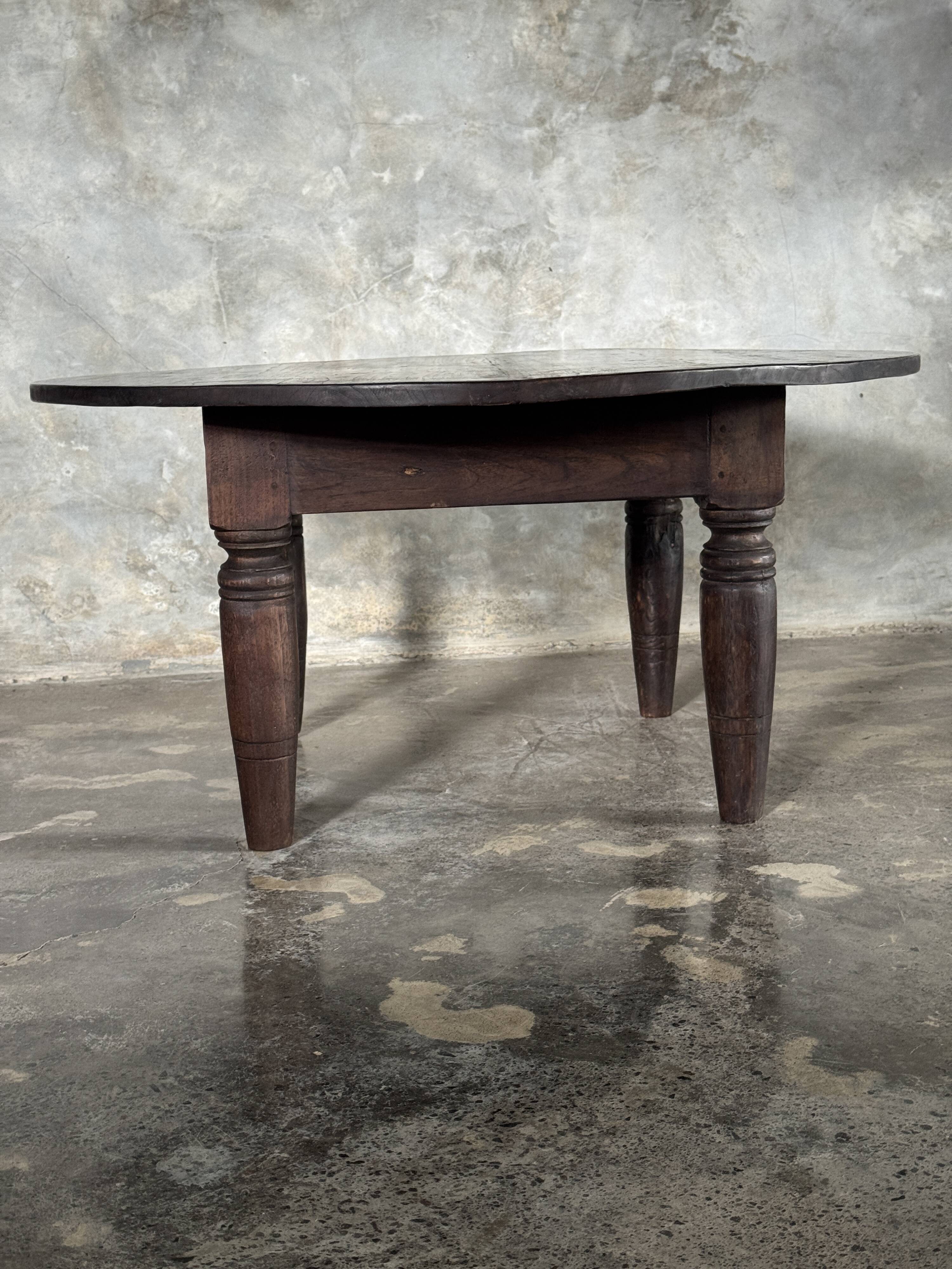 Antique round coffee table in Indonesian teak with turned legs.