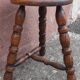 Low wooden tripod stool.