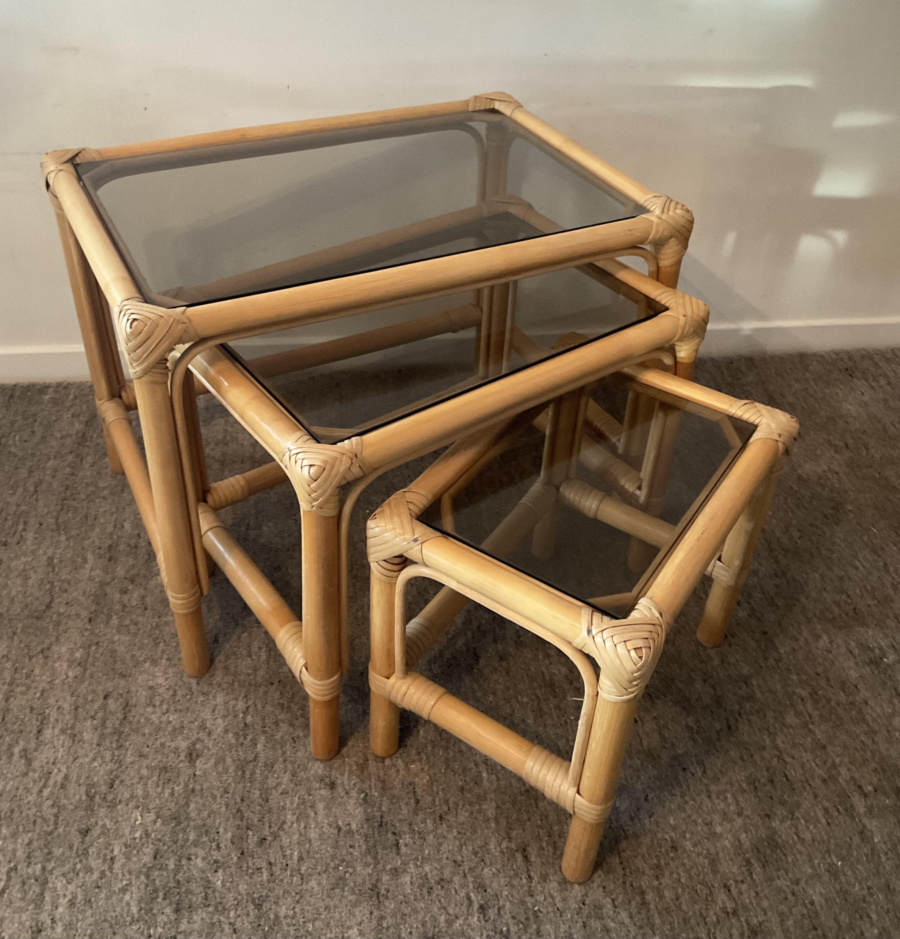 Trio of vintage pull-out tables in rattan and smoked glass 70s