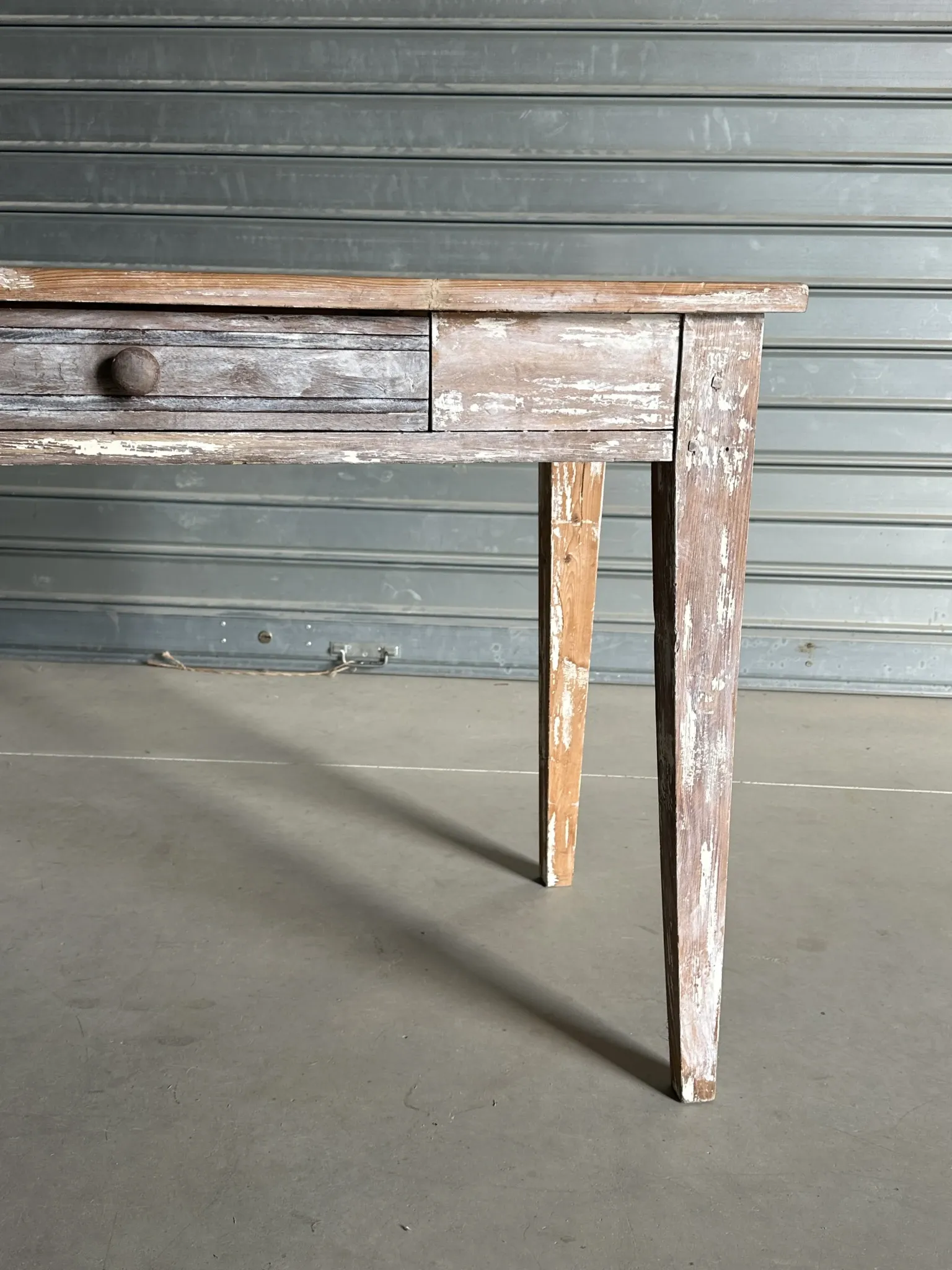 Vintage table made of raw wood with a distressed white base.