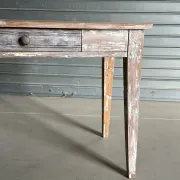 Vintage table made of raw wood with a distressed white base.