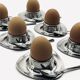 Four stainless steel egg cups and spoons