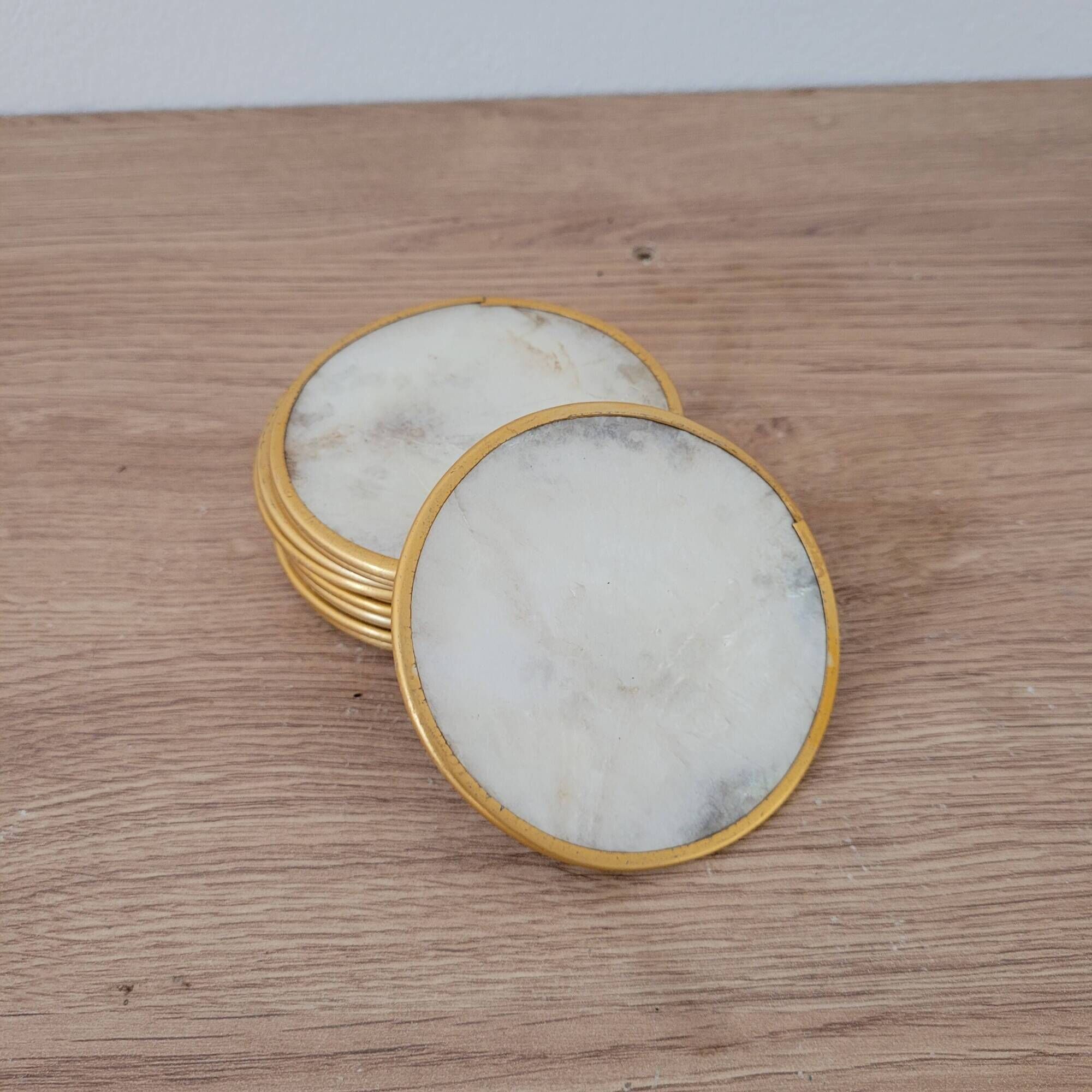 Set of 11 mother-of-pearl coasters with brass rim.